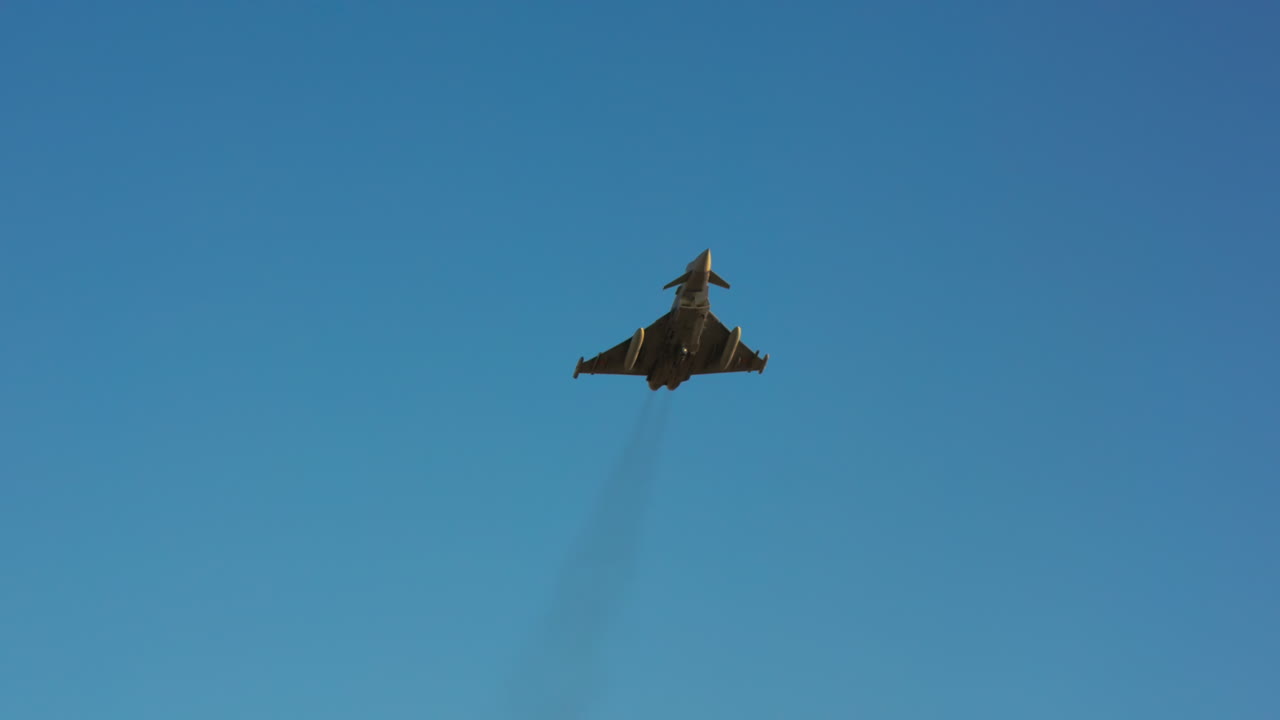 Militært jagerfly flyr på en klarblå himmel