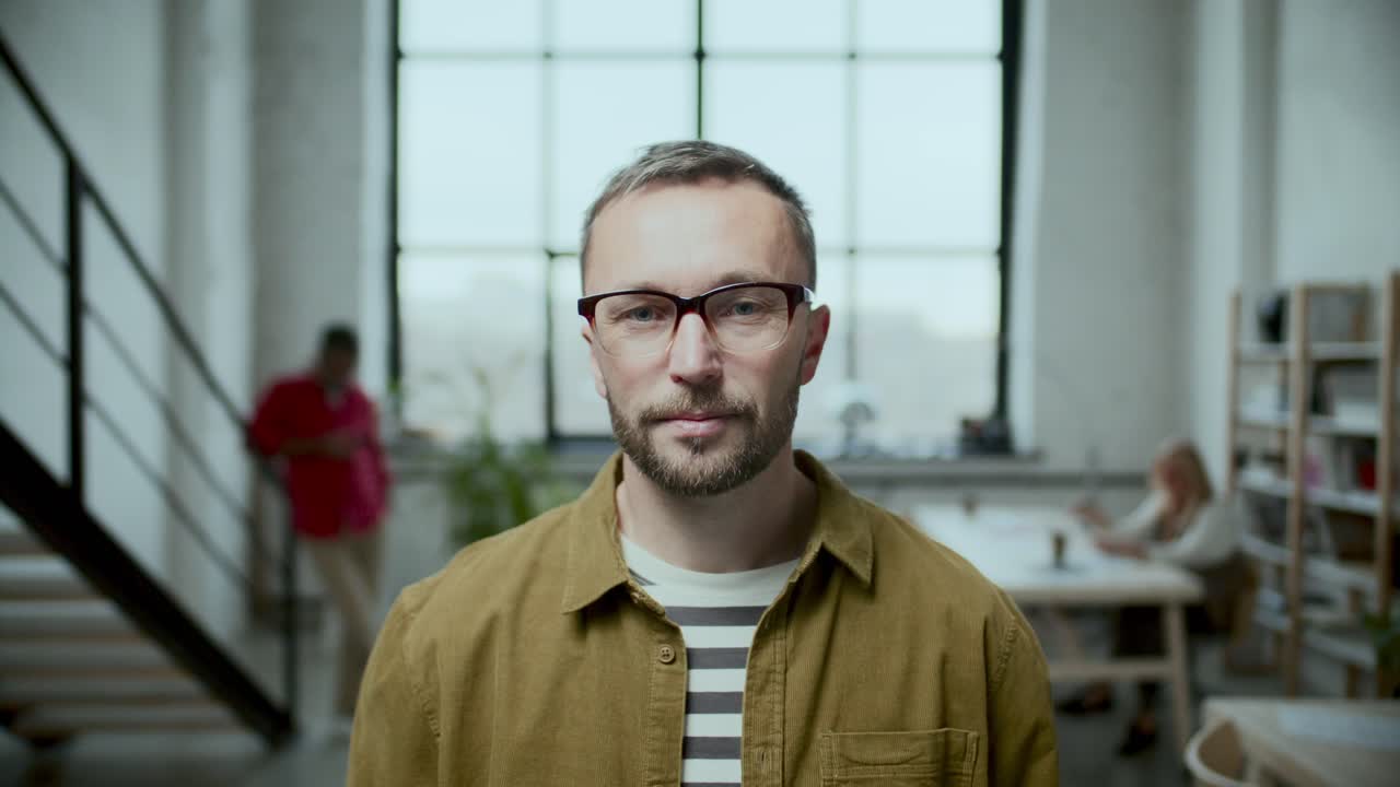 Ritratto di uomo in abbigliamento casual che posa per la fotocamera in un ufficio moderno.