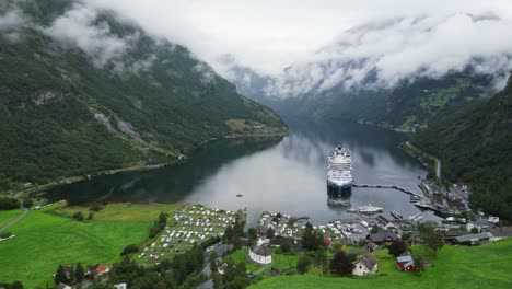 Cruise-Ship-in-Geiranger,-Norway---Scenic-Geirangerfjord-and-Small-Village-in-Stranda,-More-og-Romsdal---Aerial-Circling