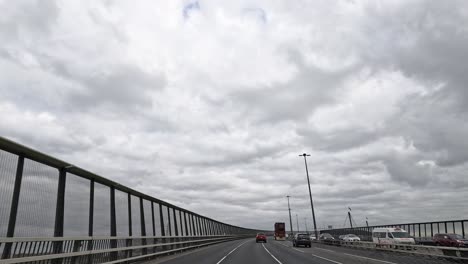 cars traveling on a bridge under cloudy skies