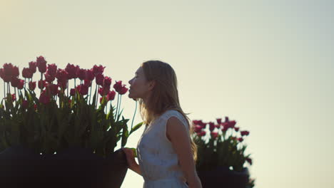 Beautiful-woman-smelling-flowers-outdoors.-Gentle-lady-enjoying-tulips-in-park.