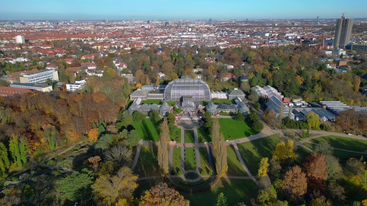 Botanical Garden Berlin 100-year old Victoria House greenhouses surrounded by autumn trees and urban landscape. Unique aerial view flight panorama overview drone shot from above