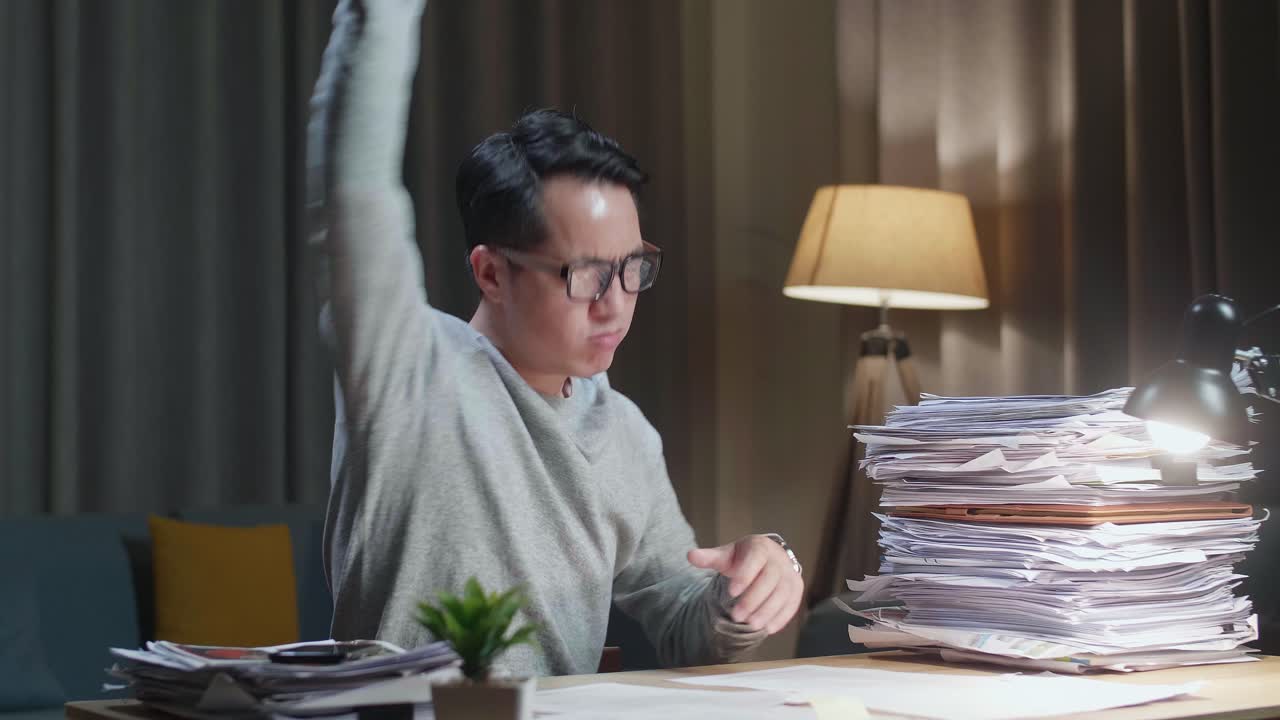 Asian Man Throwing Paper And Having Headache While Working Hard With Documents At Home
