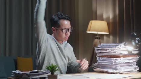 asian man throwing paper and having headache while working hard with documents at home