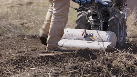 Man-pushing-a-rototiller,-working-the-land-in-Sweden,-agriculture,-medium-shot