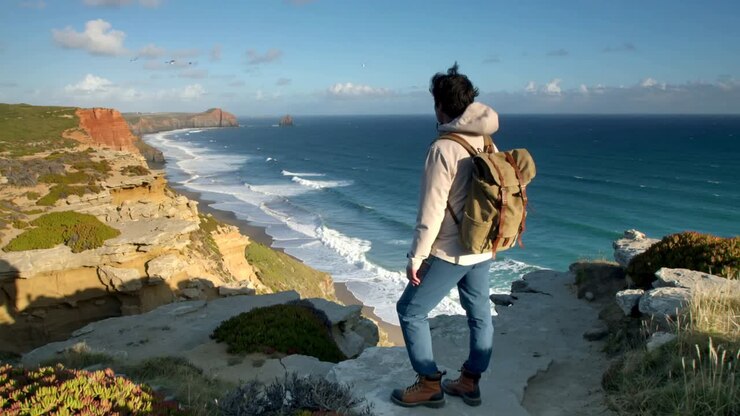 Wind, der Wanderer in Kapuzenjacke und Rucksack antreibt, der geht und den Horizont absucht, Copy Space