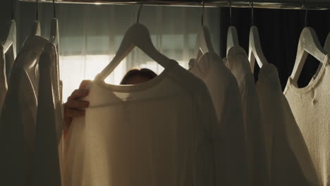 a woman chooses clothes in the dressing room. silhouette in the sun