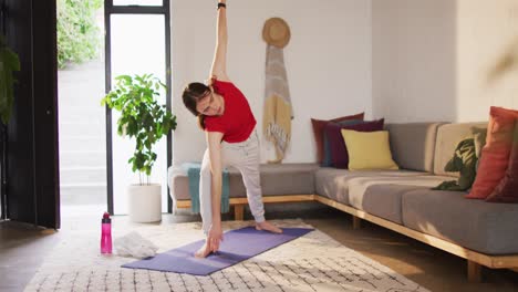 caucasian non-binary transgender woman practicing yoga, stretching