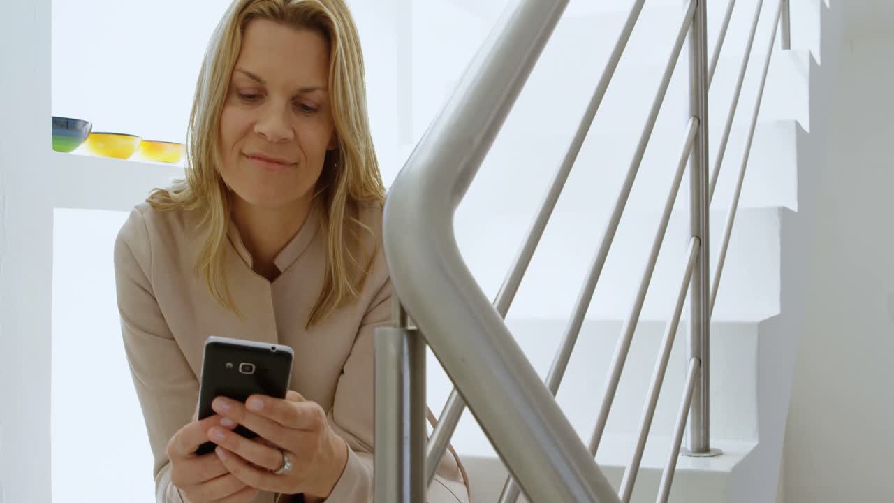 Donna che usa il cellulare sulle scale di casa 4k