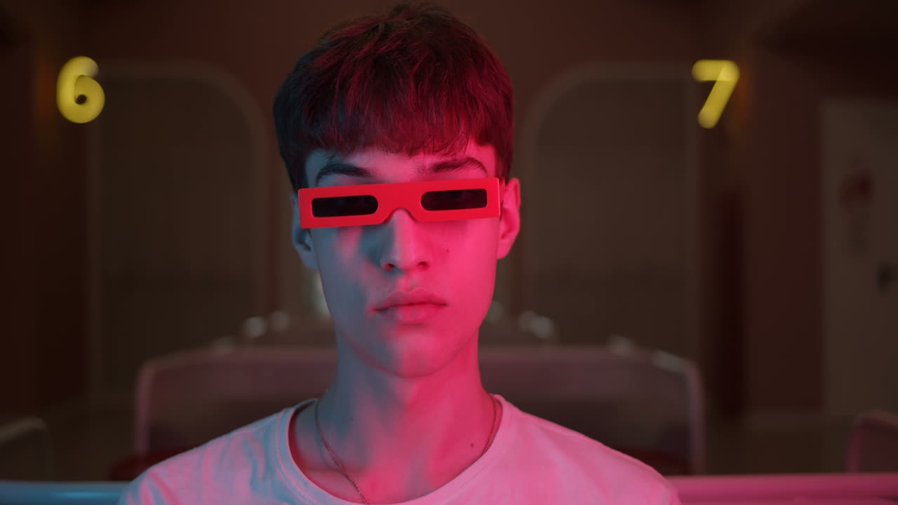 Teenager with red glasses in colorful lighting