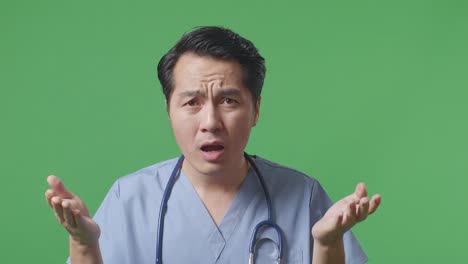 close up of asian male doctor with stethoscope showing puzzled gesture and saying what on green screen background in the hospital