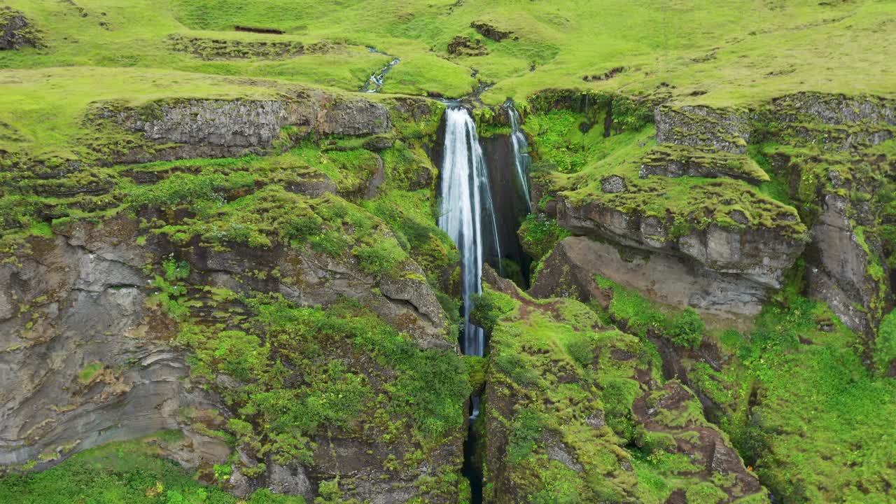 cascada gljufrabui escondida en una cueva durante el verano en islandia - retroceso aéreo