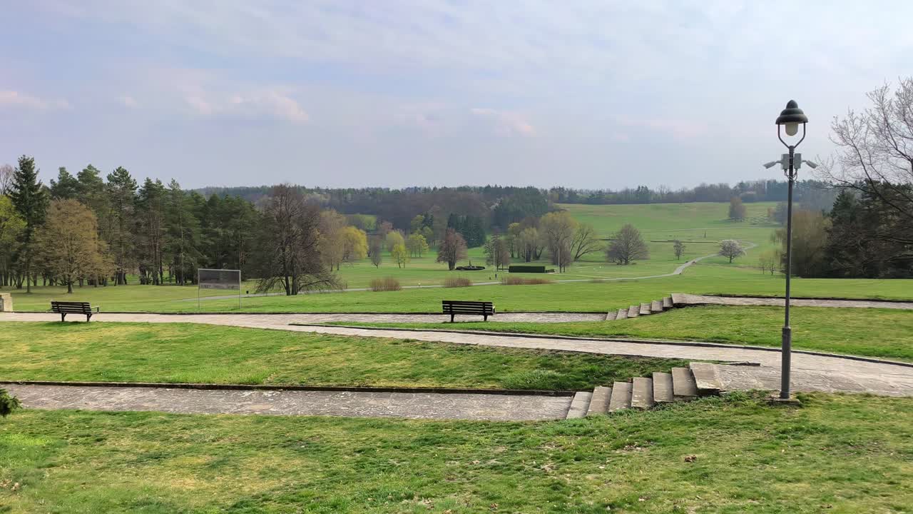 Peaceful landscape in Lidice with green fields, walking paths and benches under a soft cloudy sky. This place in the Czech Republic carries quiet atmosphere of memory, history and reflection