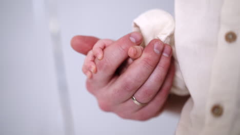 big male hand holding a tiny baby hand caressing tiny fingers. close up. father and child concept.