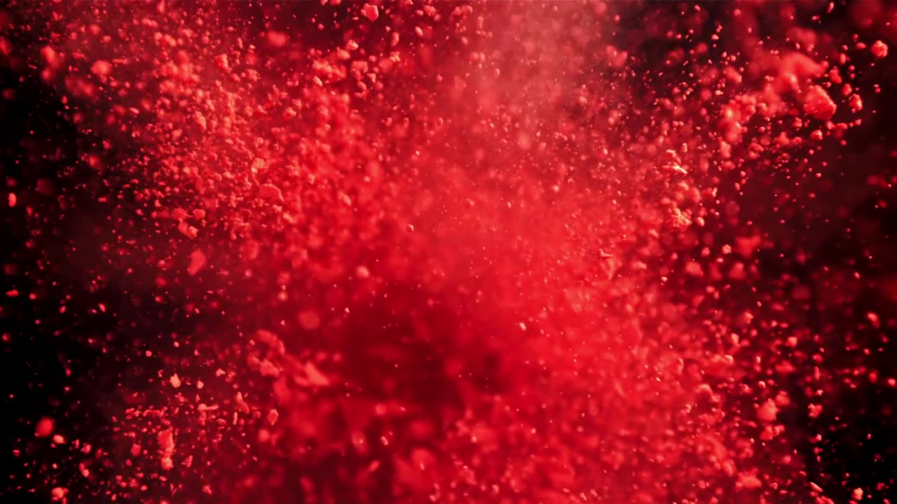 Exploze červeného prášku ve zpomaleném záběru na tmavém pozadí
