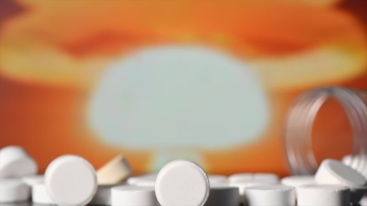 Scattered anti-radiation iodine pills, empty jar nearby, nuclear explosion on the background. Slow motion