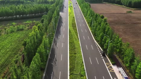 Aerial-photography-of-empty-long-city-road-lined-with-green-trees-on-side,-adding-to-the-serene,-tranquil-atmosphere-of-the-scenery