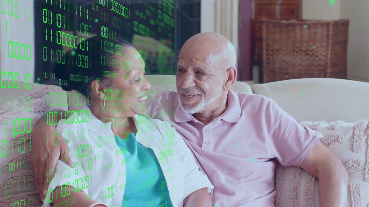 Seniors sitting on sofa watching offscreen tech, leaning, smiling while green binary code drifting