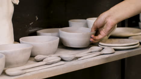 Close-Up-Of-An-Unrecognizable-Woman-Putting-A-Ceramic-Bowl-On-A-Wooden-Shelf-In-The-Pottery-Shop