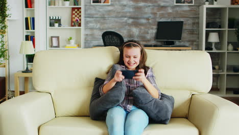 excited little girl playing video games on her phone
