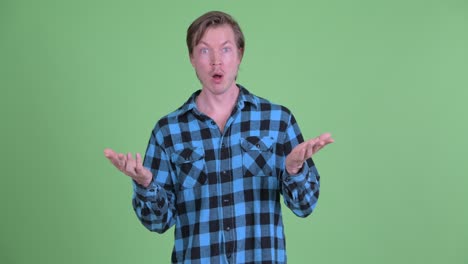 portrait of caucasian man looking surprised and shrugging shot against green studio background