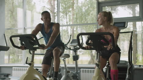 caucasian female monitor and an athletic african american man in the gym.