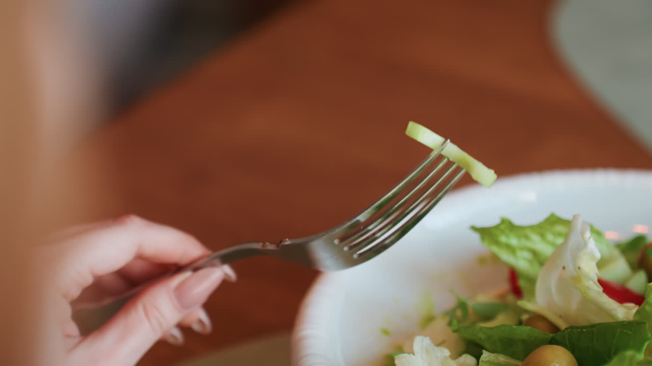 Fork lifted with curled lettuce above plate, visible hand brings bite toward mouth, warm tabletop light, shallow depth of field, subtle motion blur, crisp texture emphasis, intimate homestyle dining