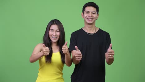 young asian couple giving thumbs up together
