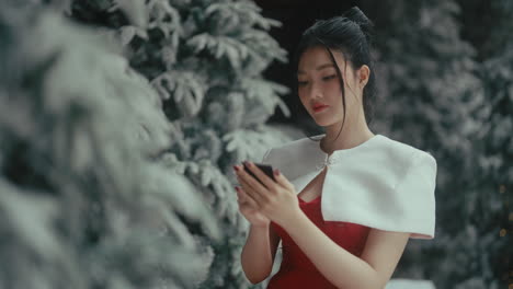 young woman using phone in christmas setting