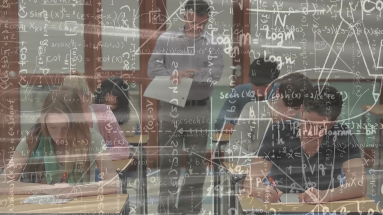 Teacher stepping into aisle distributing exam papers in math class, formulas appearing over desks
