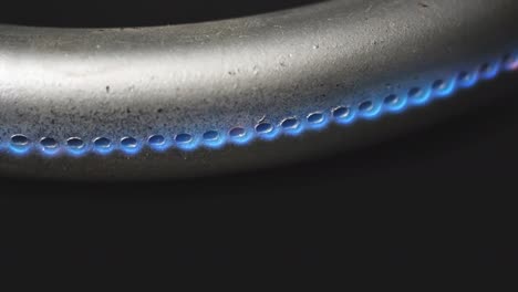 quemador de gas en el horno de primer plano en un fondo negro con una llama que se desvanece lentamente. video crudo macro 4k.