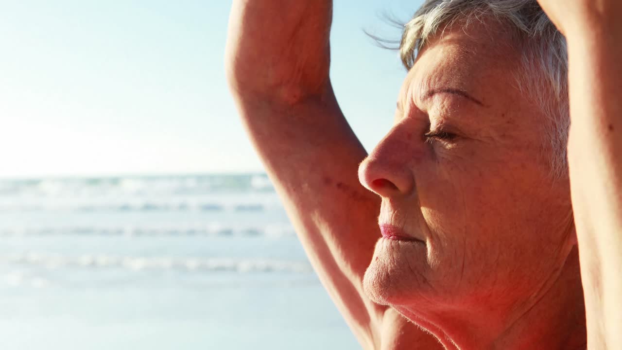 donna anziana che fa yoga sulla spiaggia