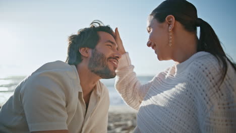 cónyuges románticos mirándose el uno al otro con amor sentados en la playa por la noche de cerca.
