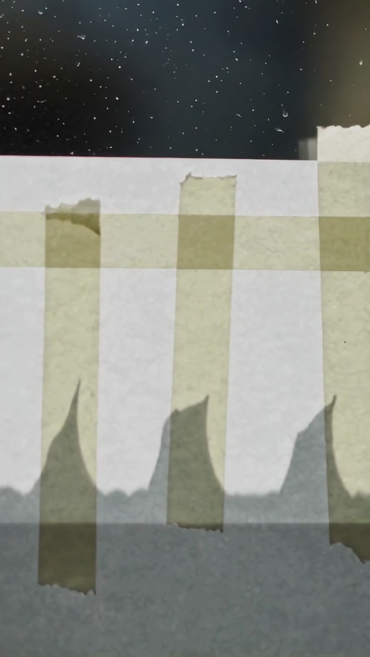 Vertical video: Shifting camera revealing white paper with yellow tape on table, varying shadows