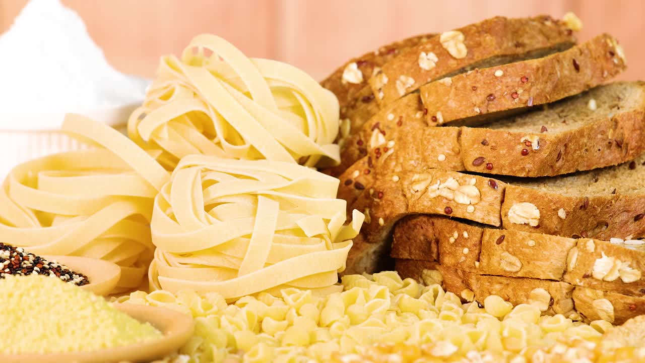 A variety of grains and breads displayed with warm lighting, highlighting textures and colors in a close-up composition