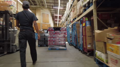 following view of young man walking through working industrial warehouse