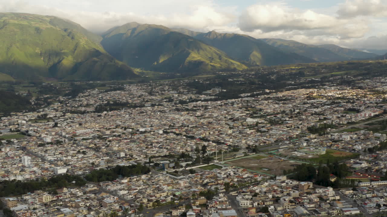 Aerial view of a sprawling city at the base of lush green mountains