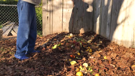 Unrecognizable-man-walking-to-a-backyard-compost-pile-and-throwing-kitchen-scraps-on-it,-then-walking-away