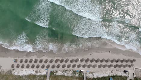 Vista-De-Arriba-Hacia-Abajo-De-La-Playa-Con-Sombrillas-En-La-Orilla-En-Vama-Veche,-Rumania--Tiro-Con-Drones