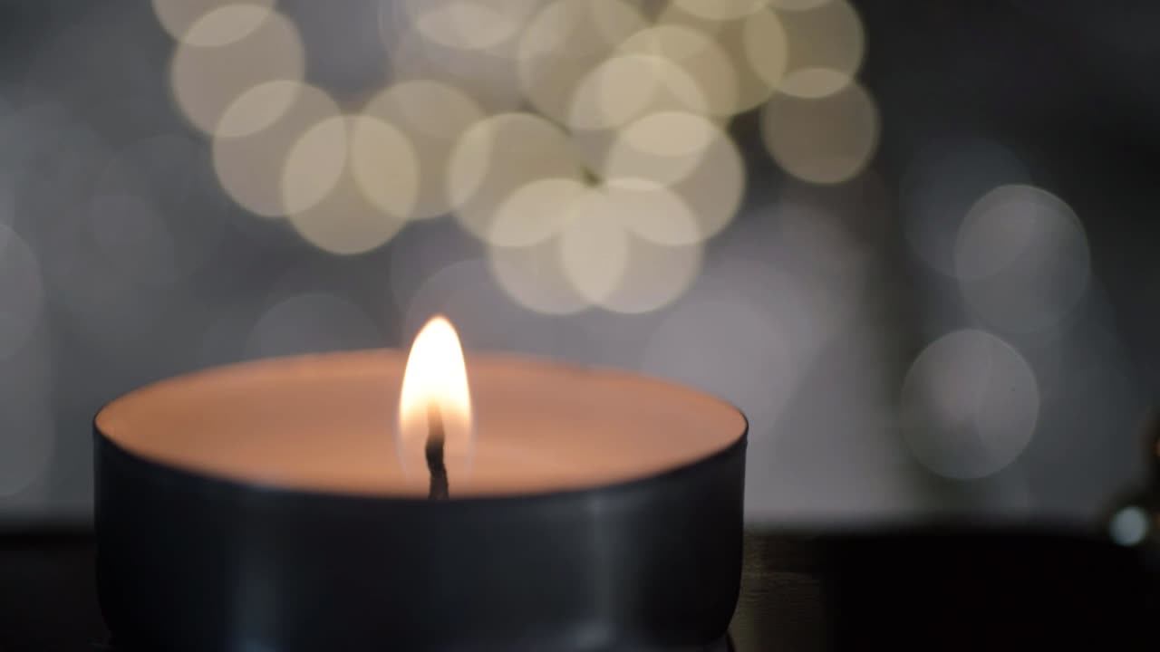 Single tea light candle with gold and silver bokeh background macro shot