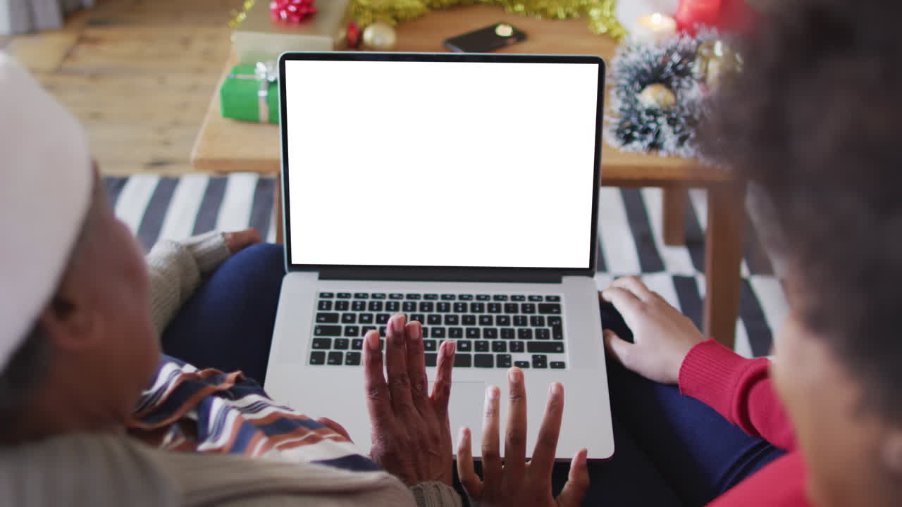 African american mother with daughter making laptop christmas video call, copy space on screen
