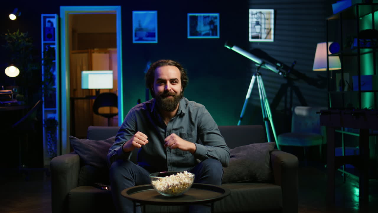 집에서 스포츠 방송을 시청하는 스타틱한 남자, 광란스러운 손짓을 하고