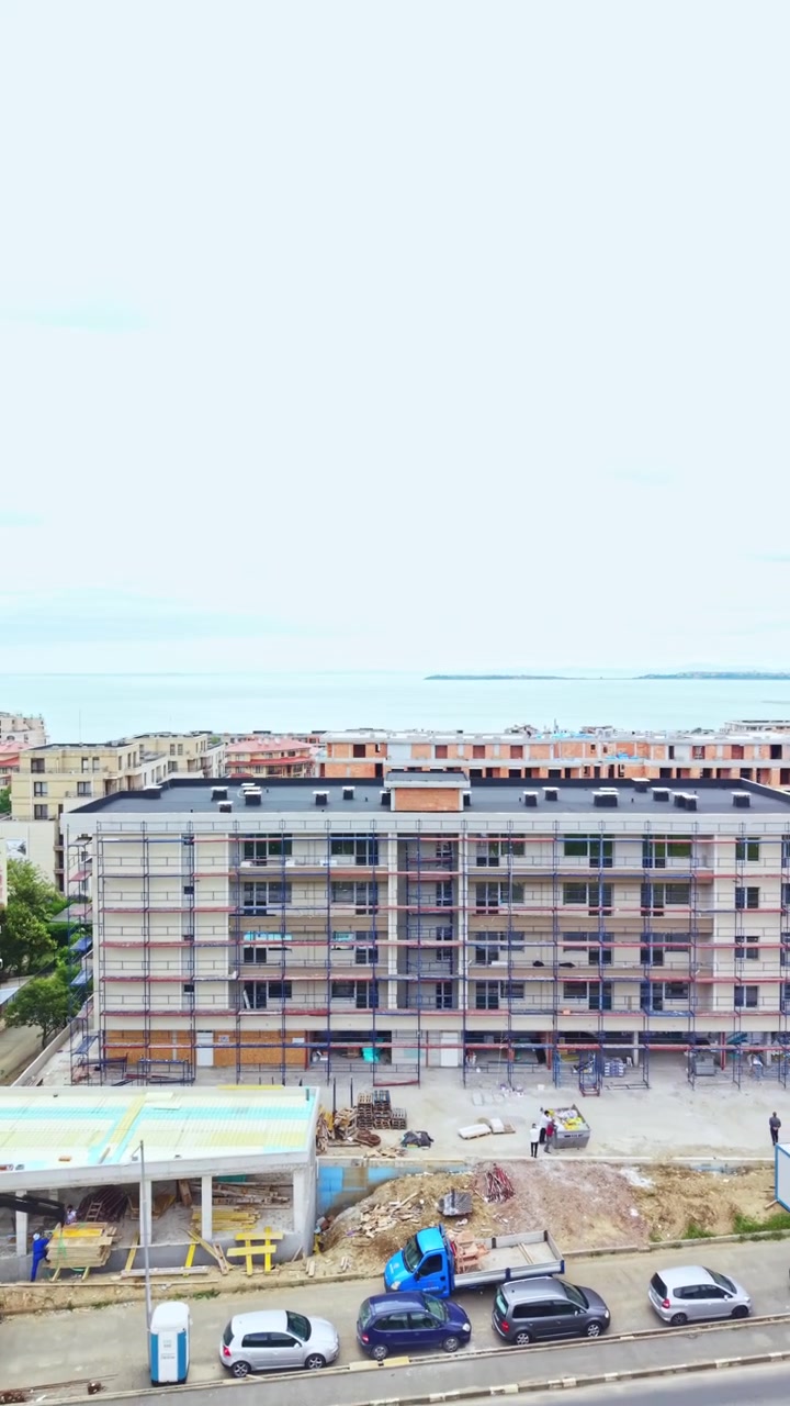 Proceso de construcción de un edificio de varias plantas con andamios y trabajadores realizando tareas durante el día en una obra.