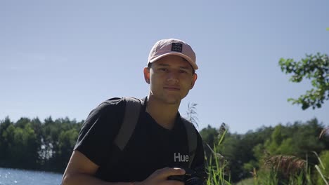 Portrait-shot-of-smart-and-young-hispanic-photographer-at-a-lake-rewatching-his-pictures