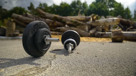 a barbell and a dumbbell positioned on the asphalt surface - close up