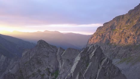 rugged mountain peaks and narrow sharp ridge high in mountains of romania with stunning sunset sky filled with purple and red