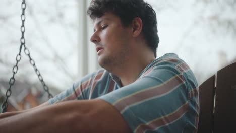 man writing and playing guitar on a porch