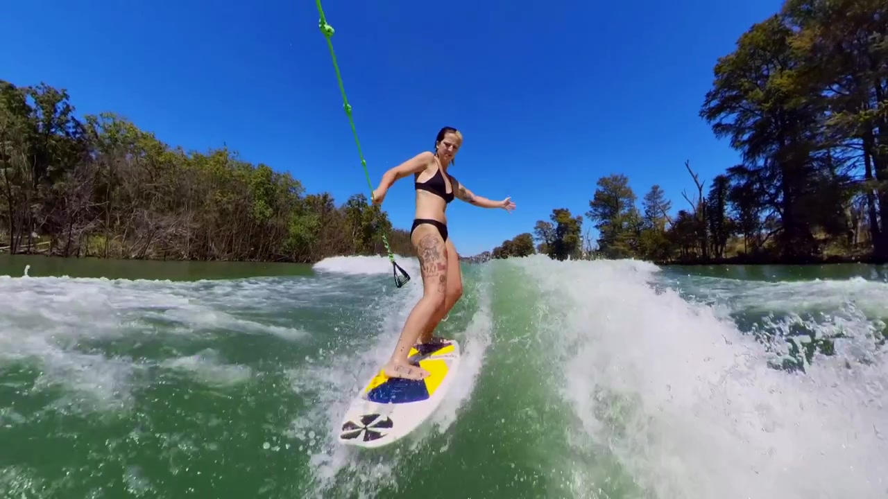 girl wakesurfing behind a boat in the summer