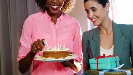 Businesswoman-lighting-candles-on-cake-with-colleague