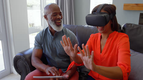 front view of mature black woman gesturing and using virtual reality headset in comfortable home 4k